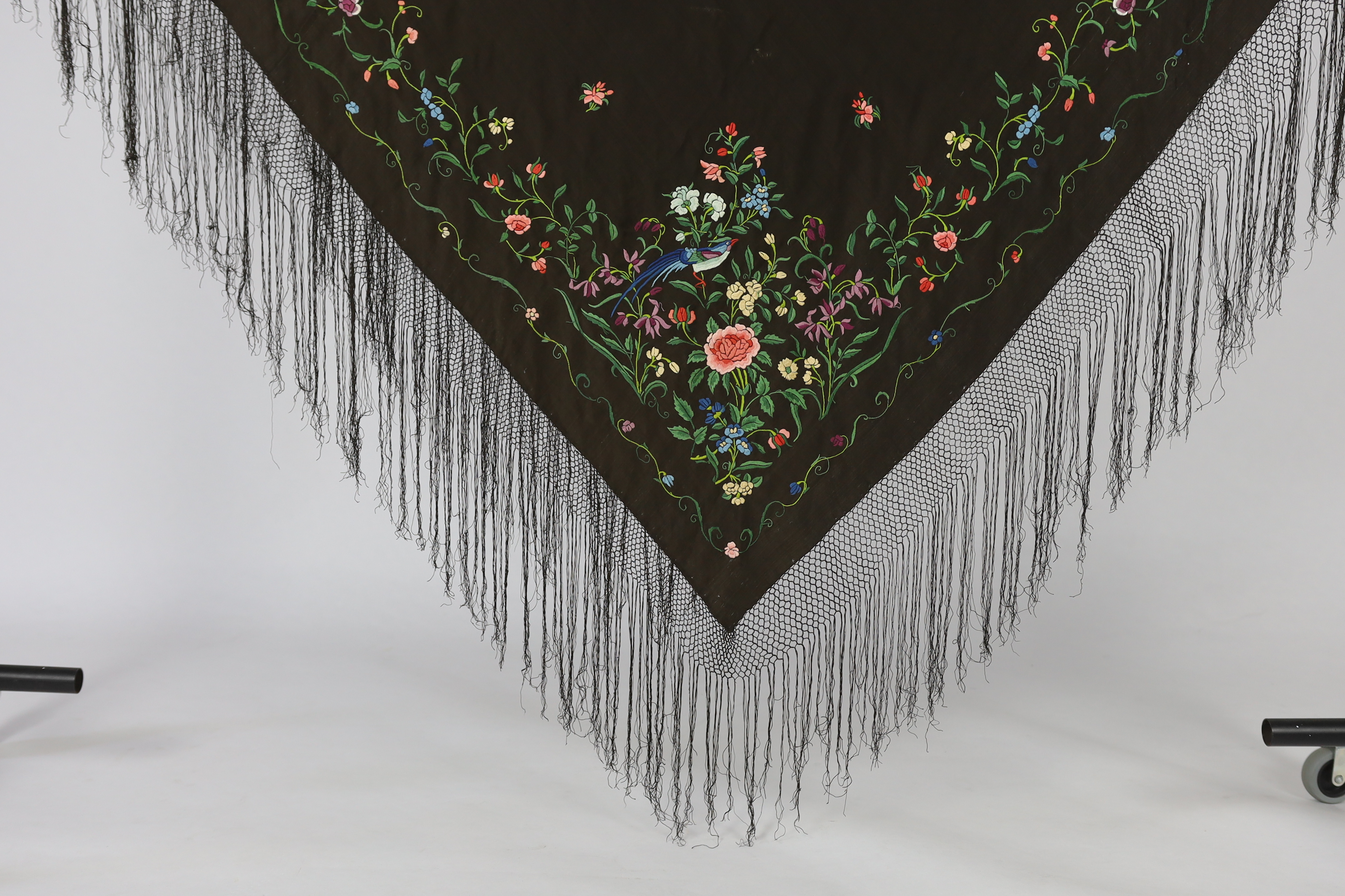 A Chinese silk shawl, circa 1900, embroidered with polychrome threads with birds and flowers against a black silk ground, 164cm sq.